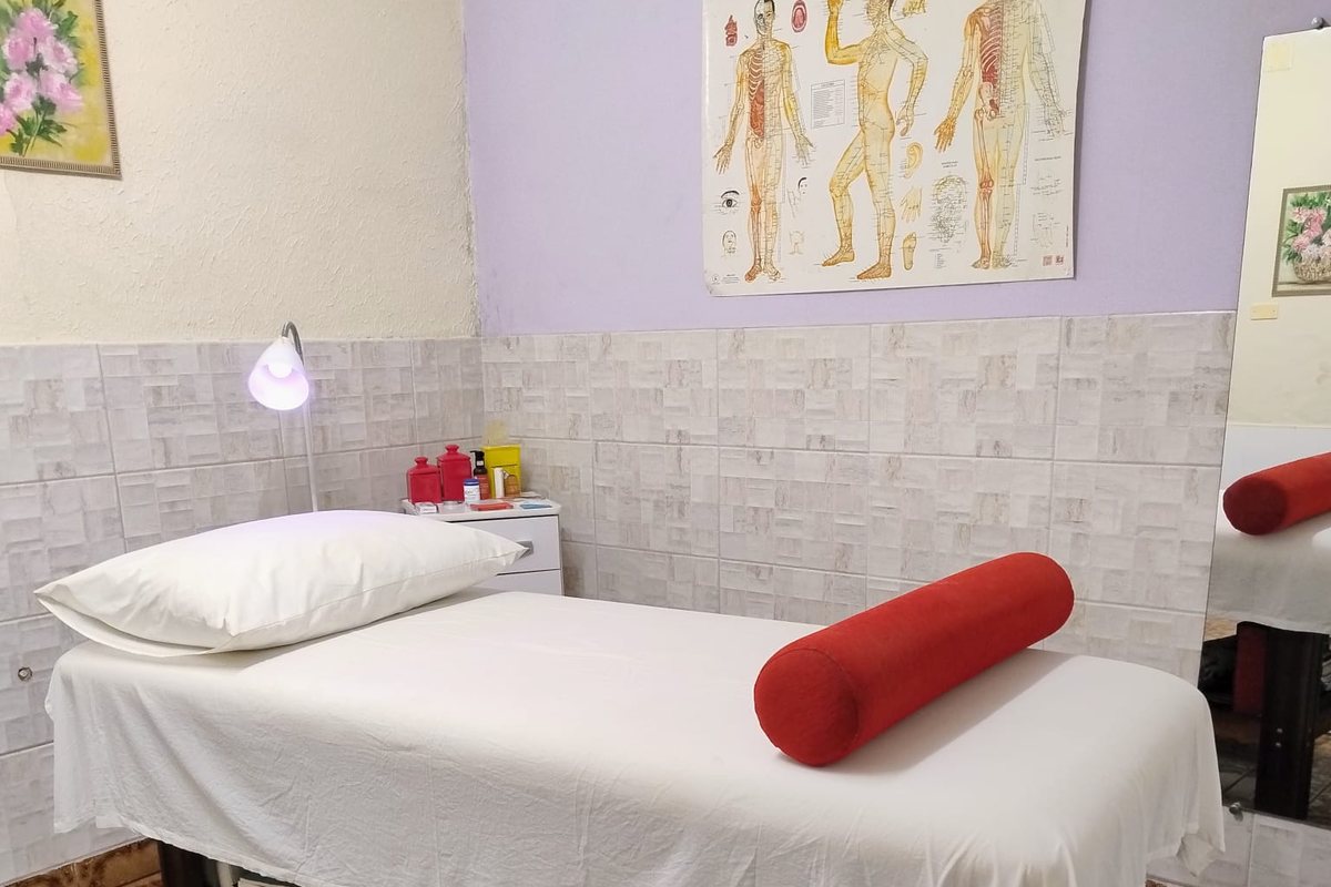 Sala de atendimento da Néria Santos, com maca, lâmpada e quadro com os pontos de acupuntura